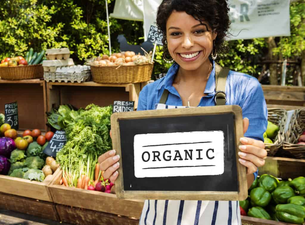 woman holding sign in front of organics