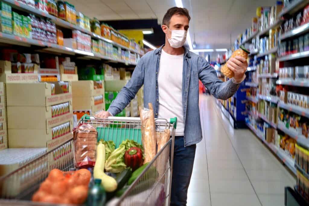 Man with mask grocery shopping using savvy grocery shopping tips